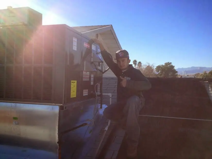 HVAC technician performing AC Tune-Up on a rooftop unit in Lewisville